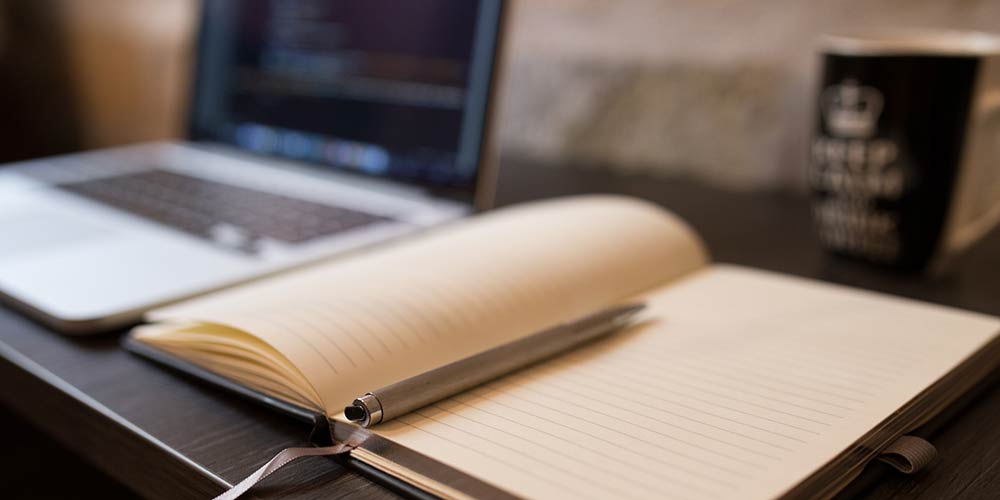 Paper notebook and laptop computer on a desk