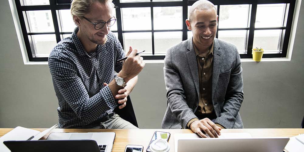 Men smiling and looking at a computer screen